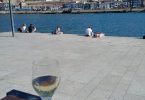 Photograph with a glass of white win on a table with Porto's river, other side of the river, and blue skies
