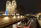 Notre Dame at night with boat on Seine river to the right