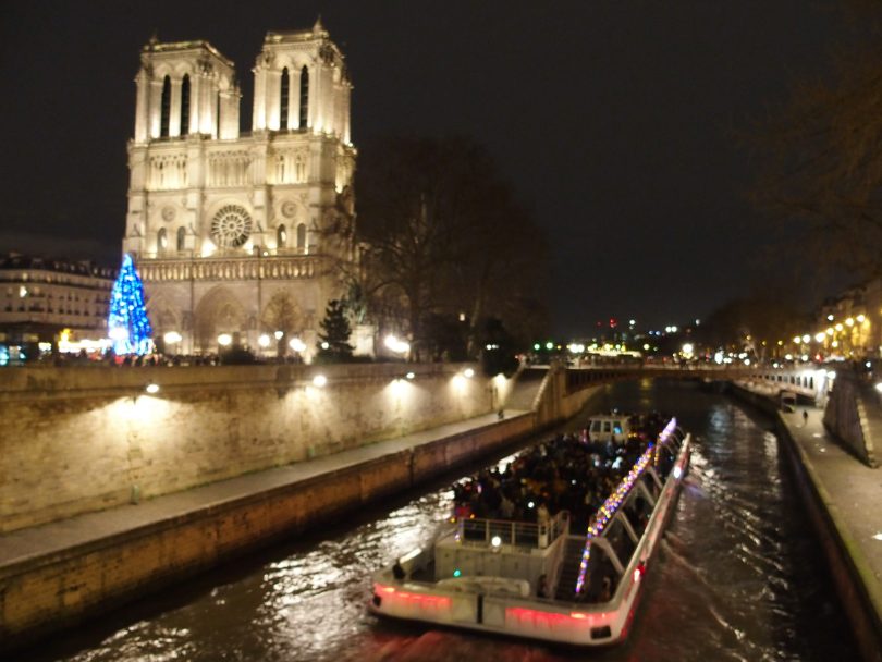 Notre Dame at night with boat on Seine river to the right