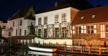 Bruges (Belgium) by night. A small boat near a row of old houses